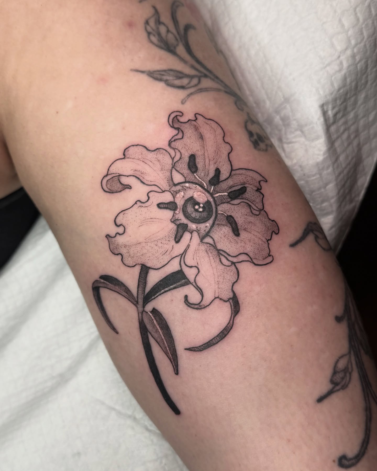 Eyeball lily on the back of the arm 👁️ Thanks soo much!! 💌 scaledwingsart@gmail.com or DM to book , I’d love to do more 
